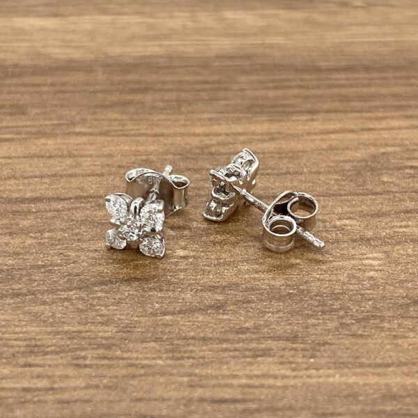 A pair of diamond stud earrings on a wooden table.
