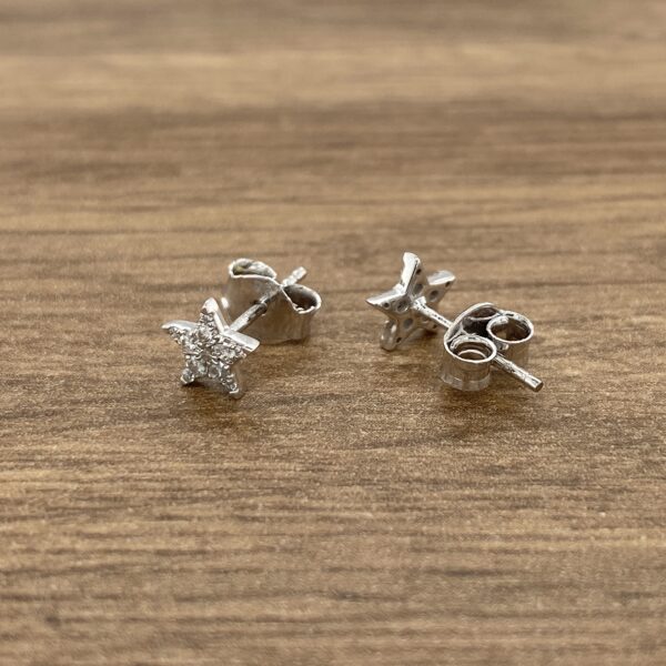 A pair of silver starfish stud earrings on a wooden table.