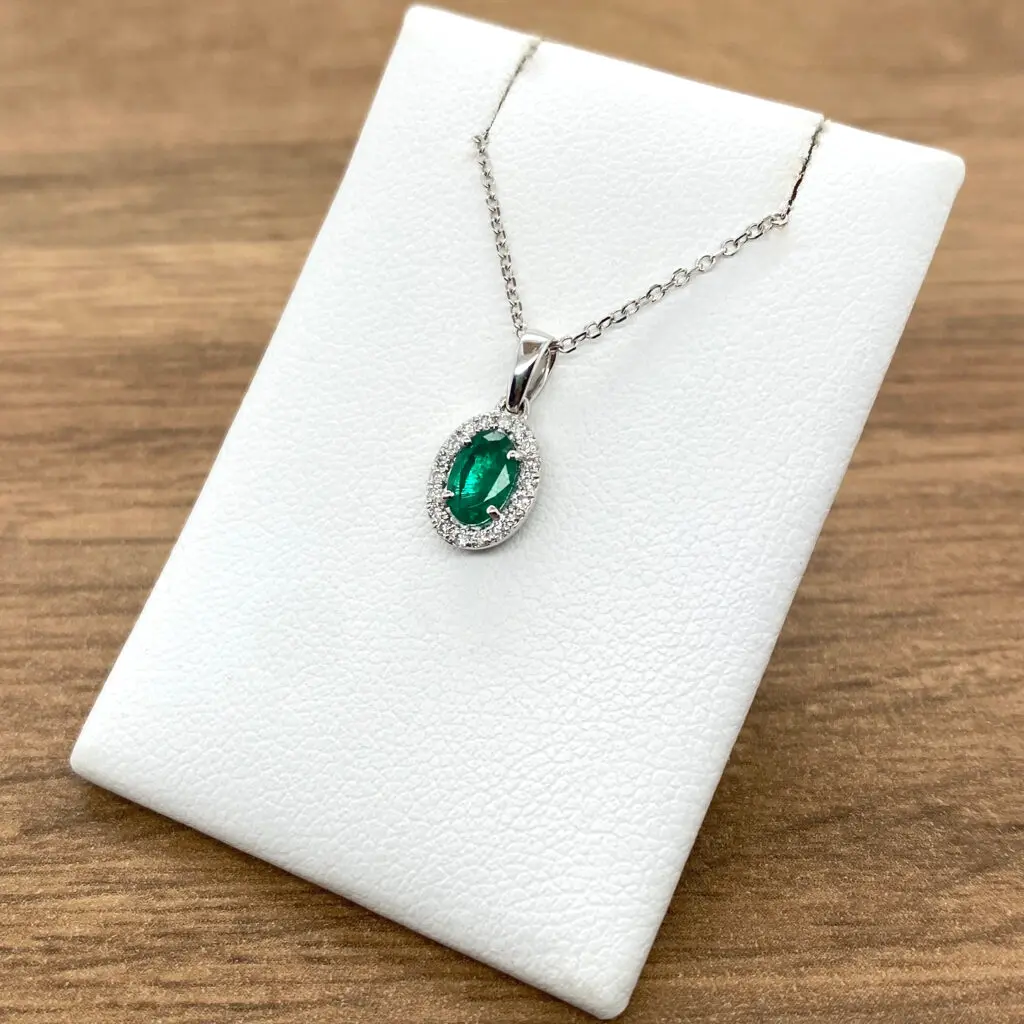 Emerald and diamond pendant on a white background.