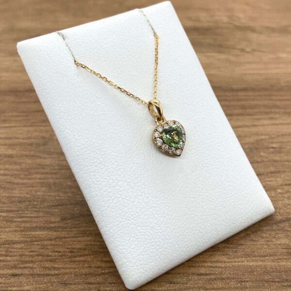 Gold necklace with green gemstone heart pendant.