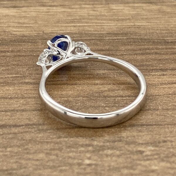 Side view of a silver ring with a blue gemstone.
