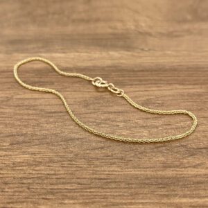 A gold chain on a wood surface.