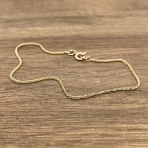 A gold chain on a wood surface.