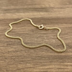 A gold chain bracelet on a wooden table.