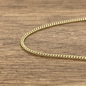 A gold chain on a wooden table.