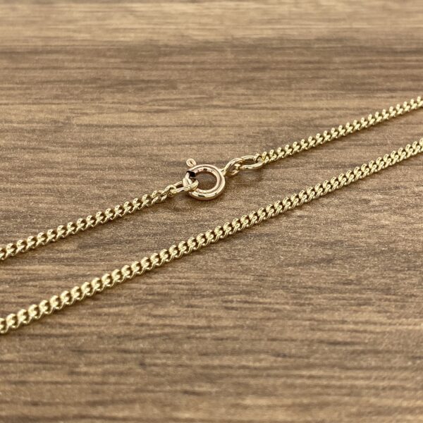 A gold chain on a wooden table.