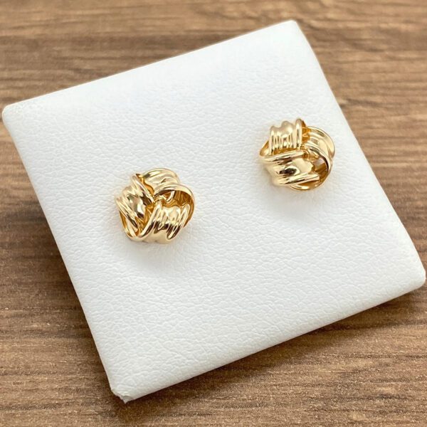 A pair of gold plated stud earrings on a white surface.