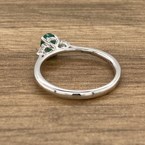 Silver ring with green gemstone and filigree.