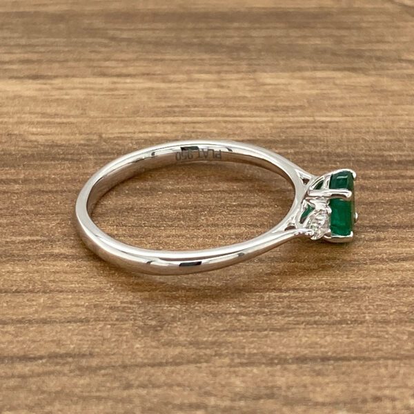 Emerald and diamond ring on wooden background.