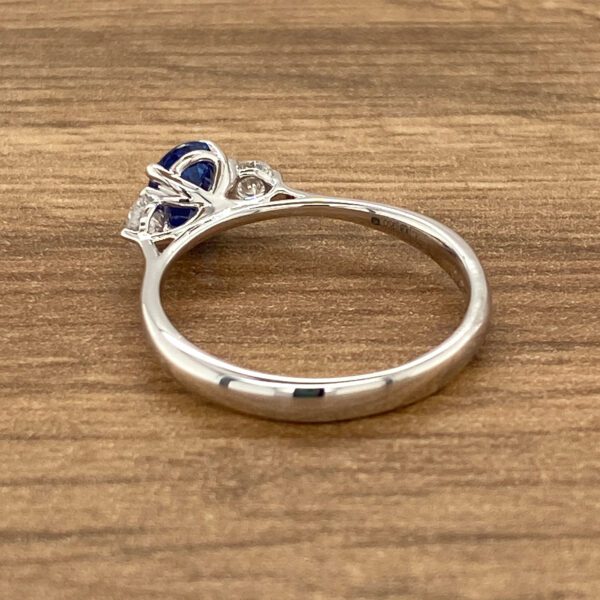 Side view of a silver ring with a blue sapphire.