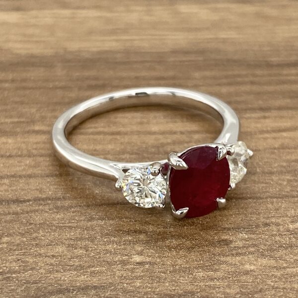 Ruby and diamond engagement ring on wood.