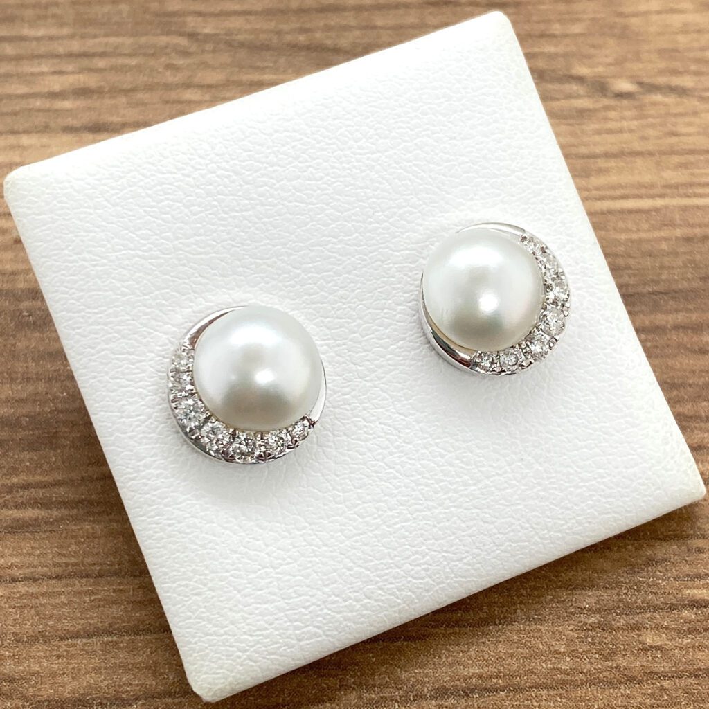 A pair of white pearl and diamond stud earrings.