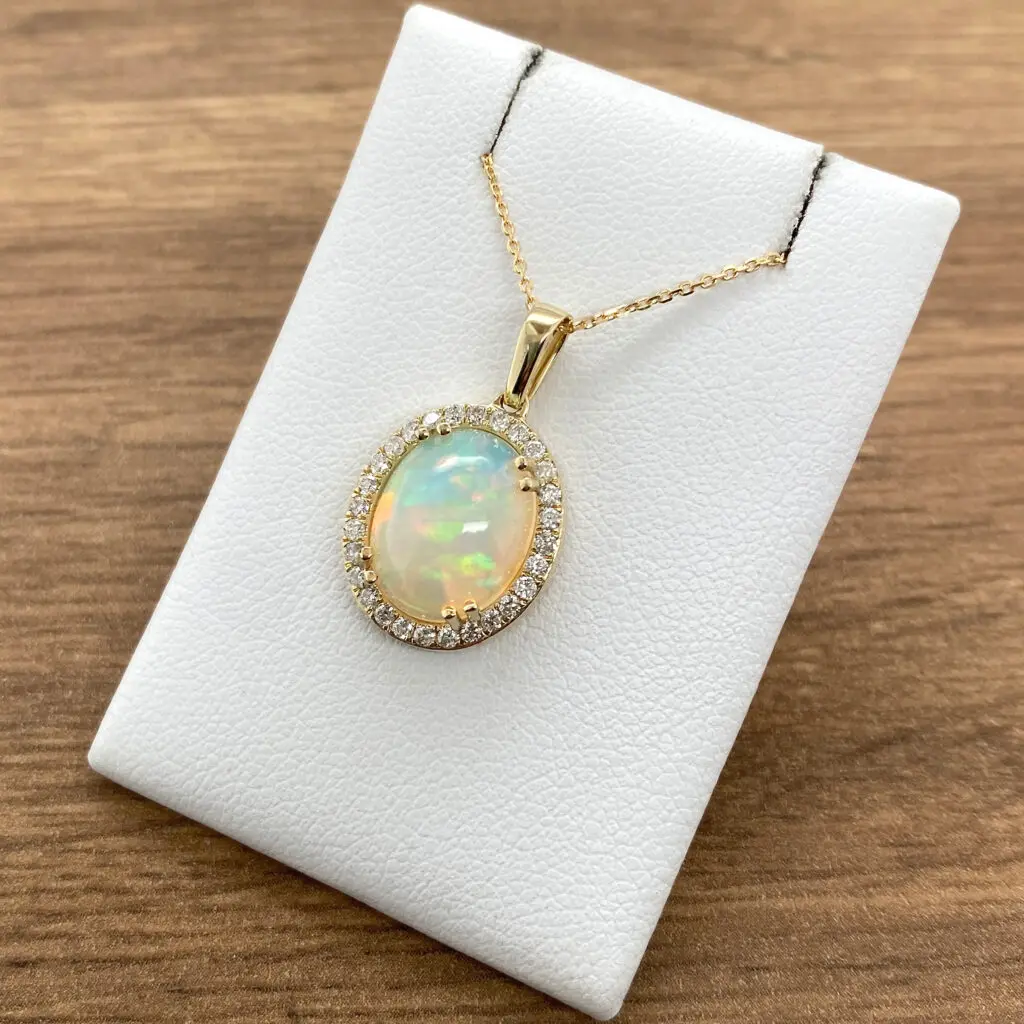 An oval opal and diamond pendant on a white background.