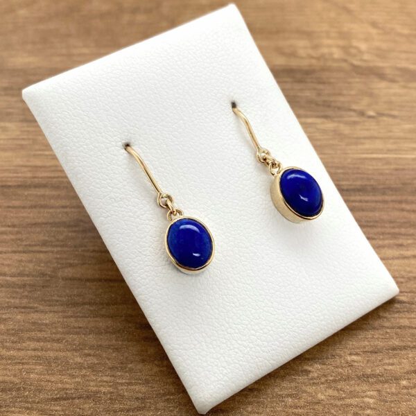 Gold earrings with oval lapis lazuli stones.