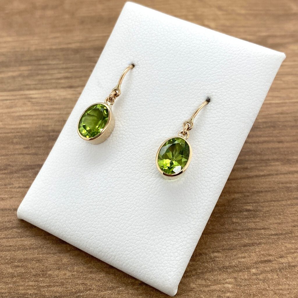 Gold earrings with green oval gemstones.