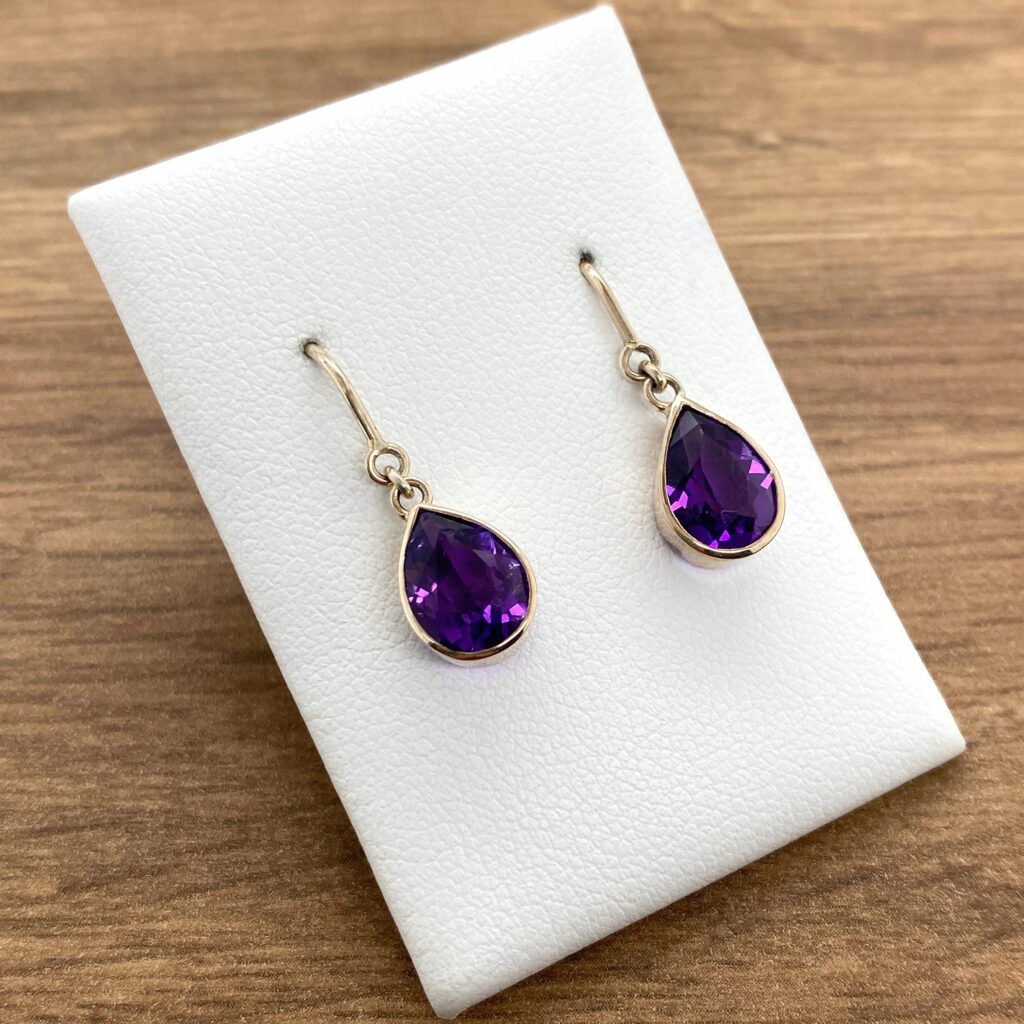 Amethyst teardrop earrings on white background.