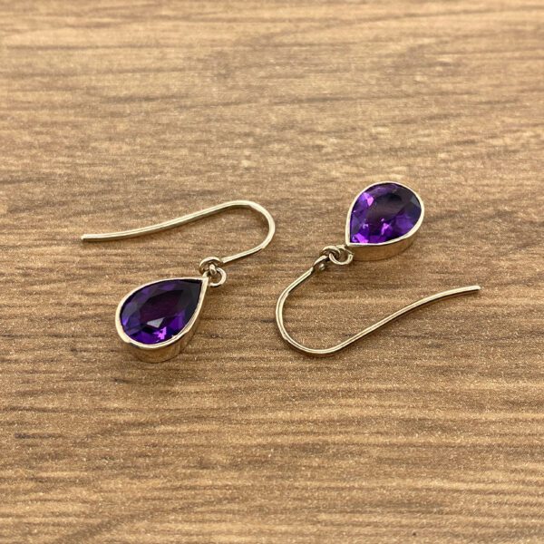 Gold earrings with purple teardrop stones.