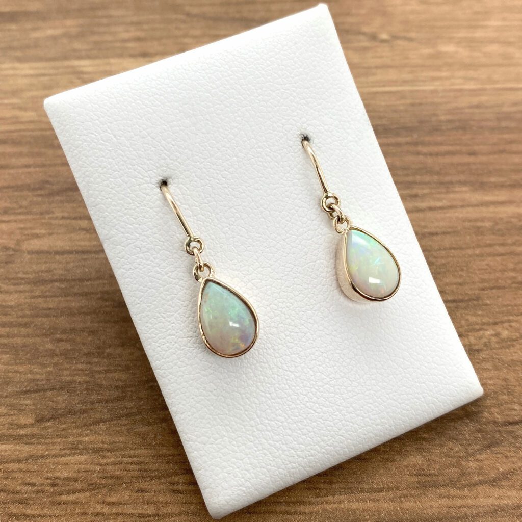 Gold teardrop opal earrings on display.