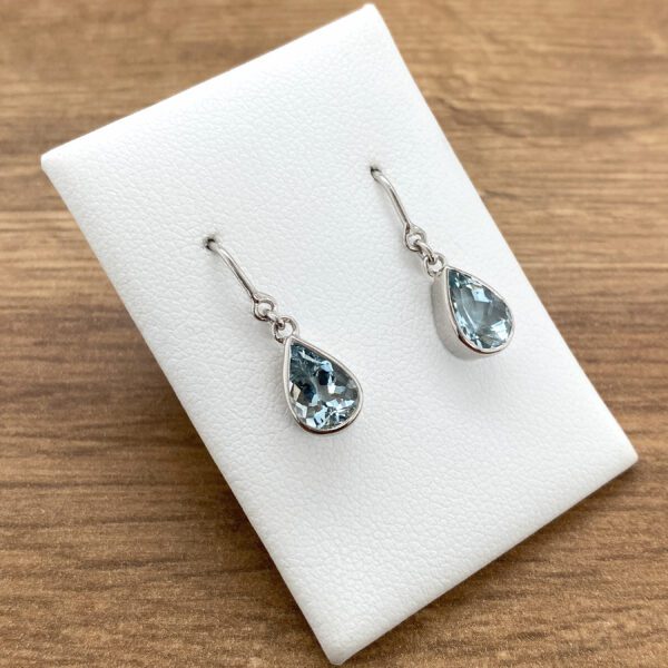 A pair of blue topaz earrings on a white background.