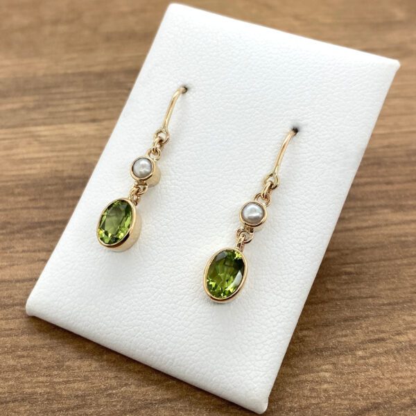 Gold earrings with green stones and pearls.