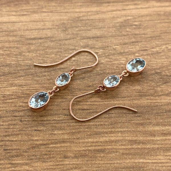 Rose gold earrings with blue topaz stones.