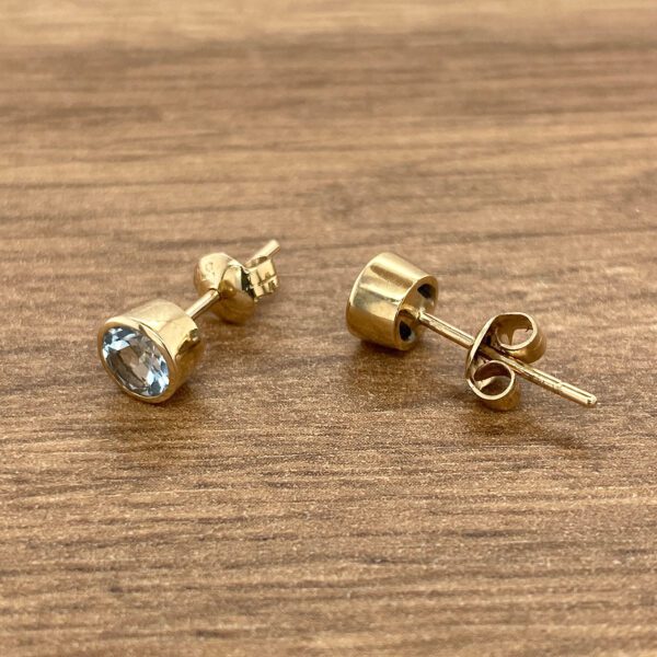 Gold earrings with oval blue gemstones.