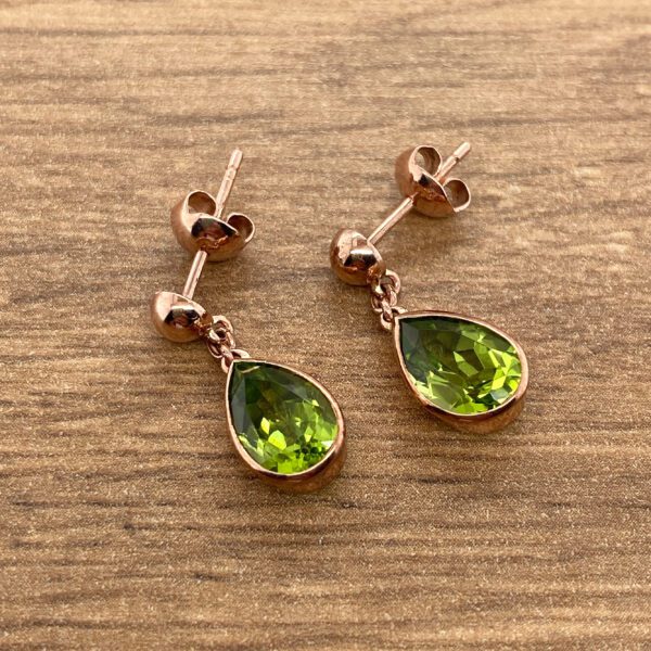 Rose gold earrings with green gemstones.