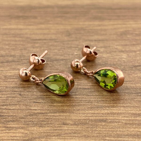 Rose gold earrings with green pear-shaped stones.