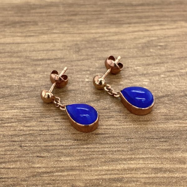 Rose gold earrings with blue teardrop stones.