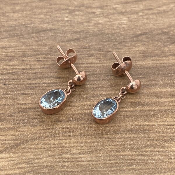 Rose gold earrings with blue gemstones.