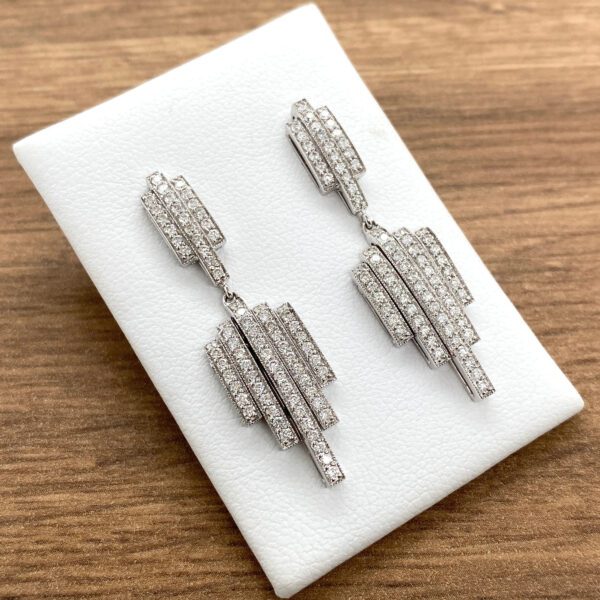 Diamond drop earrings on white display.