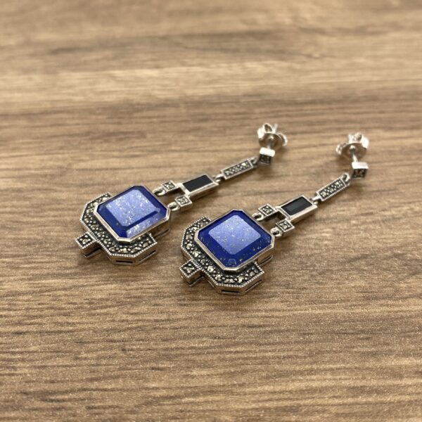 Silver earrings with blue gemstone and black accents.