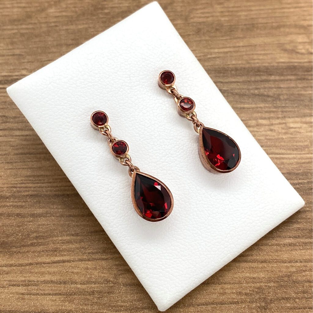 A pair of red garnet earrings on a white table.