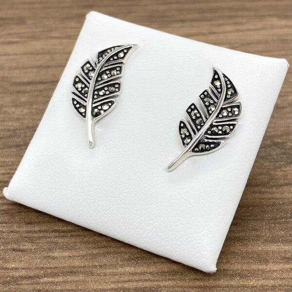 A pair of Silver & Marcasite Leaf Stud Earrings on a white plate.