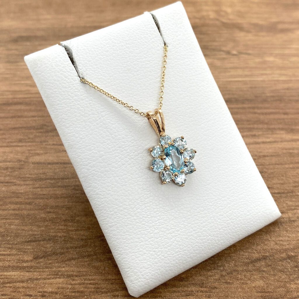 Gold necklace with blue gemstone pendant.