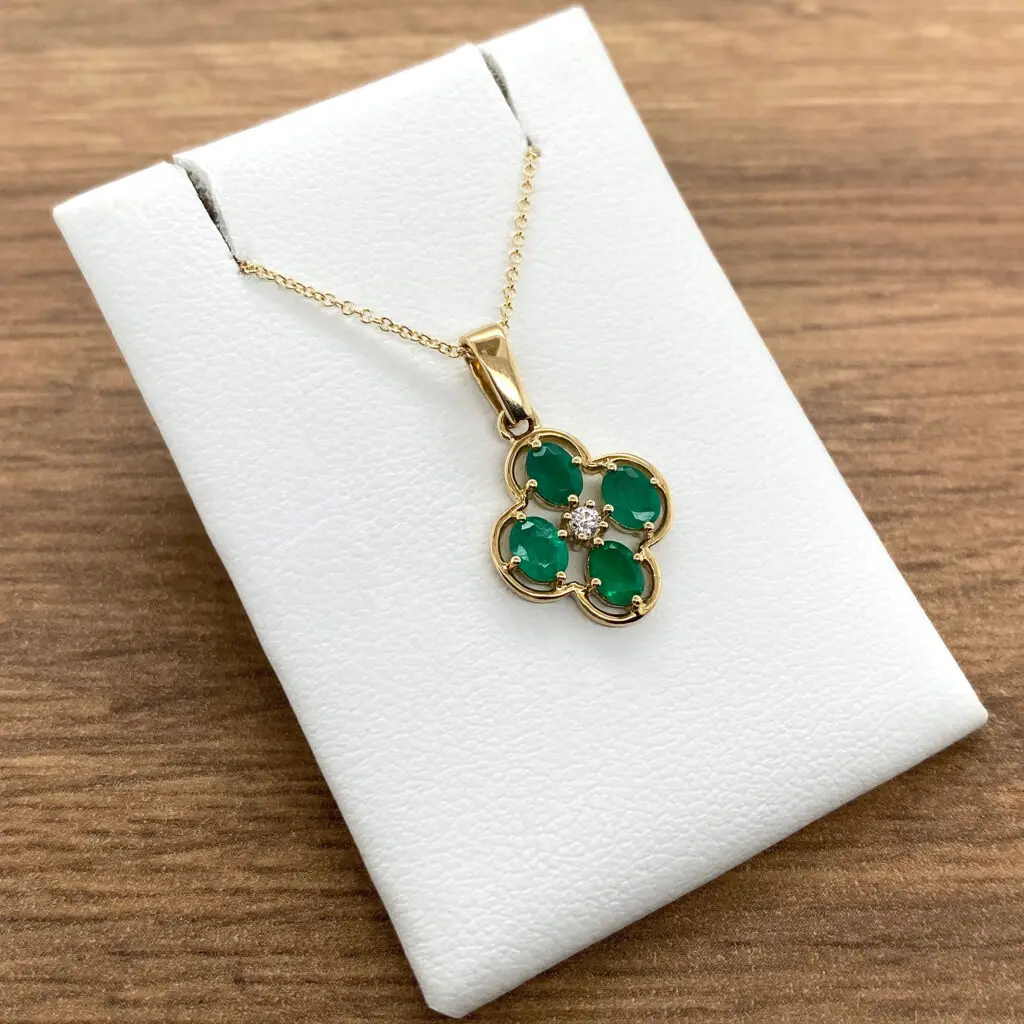 18k yellow gold emerald and diamond pendant on a white background.