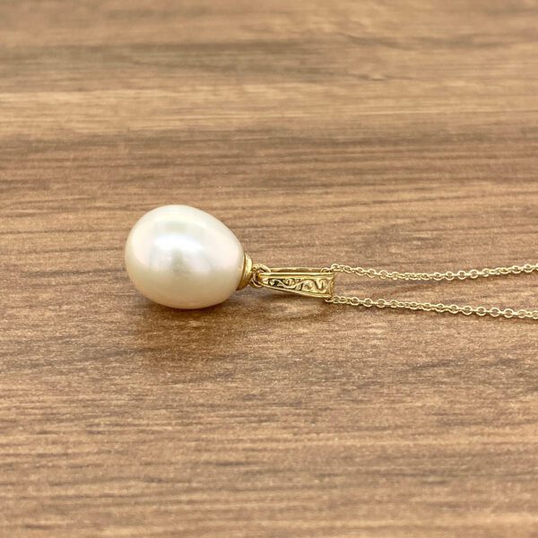 A white pearl pendant on a gold chain.