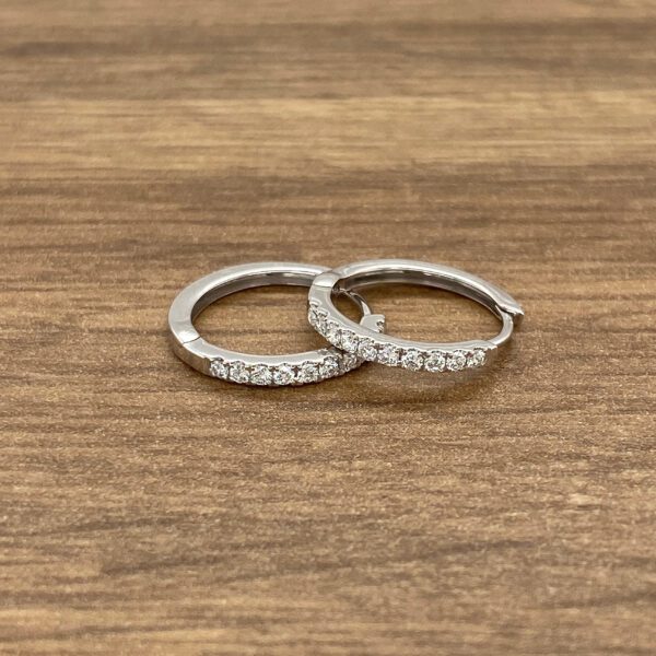 Diamond hoop earrings on wooden surface.