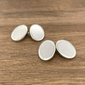 Two oval cufflinks on a wooden table.
