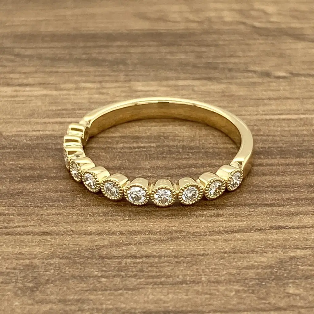 A yellow gold ring with round diamonds on a wooden table.