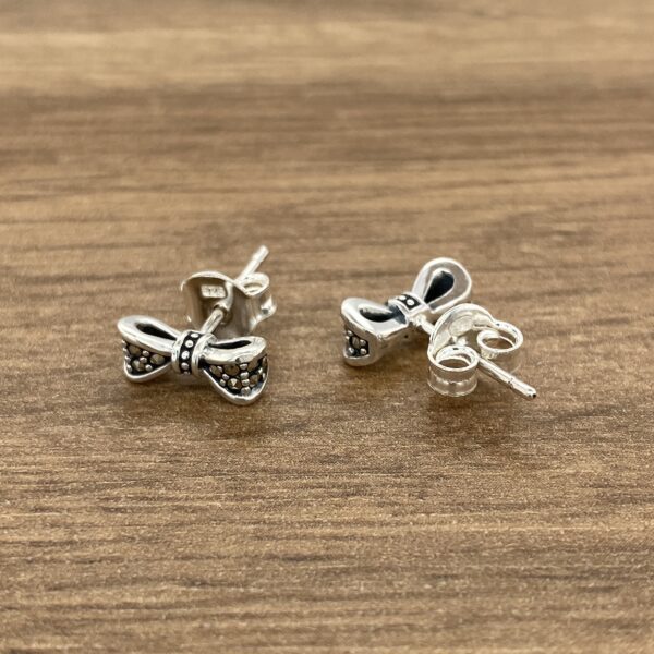 Silver bow stud earrings with black accents.