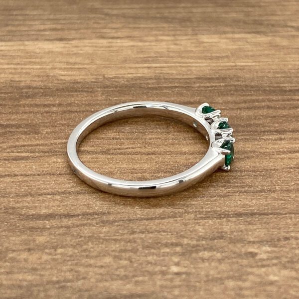 Silver band with five emerald stones.