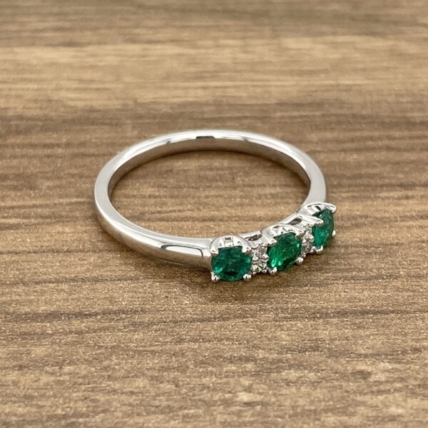 Emerald and diamond ring on wood.