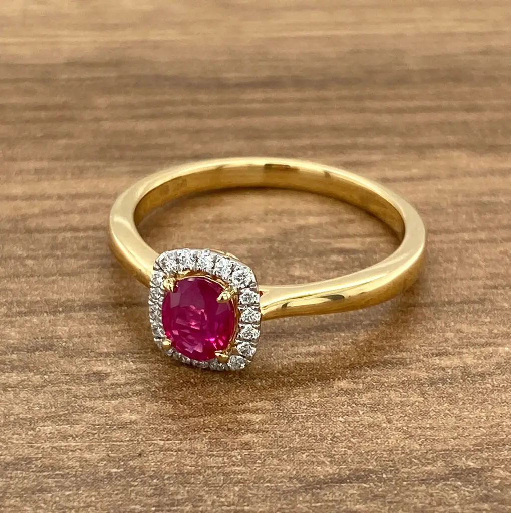 A yellow gold ring with a ruby stone and diamonds.
