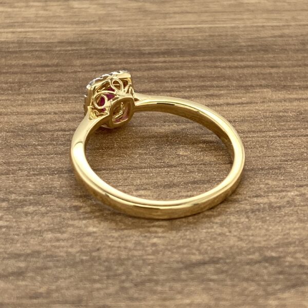 A yellow gold ring with a pink sapphire stone.