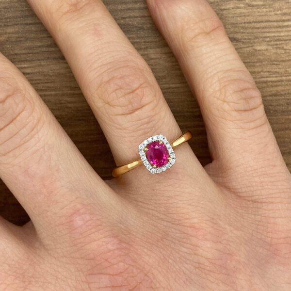 A woman's hand with a pink sapphire and diamond ring.