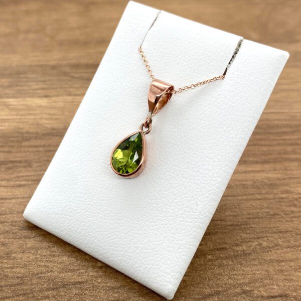 Rose gold pendant with green gemstone.