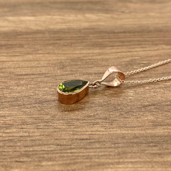 Gold necklace with green pear-shaped stone.