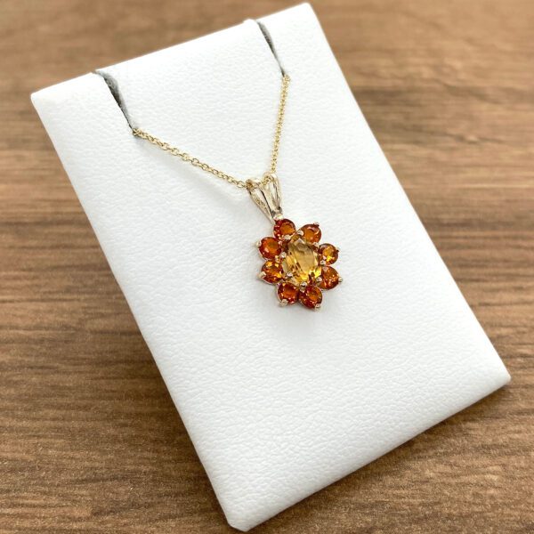 Gold necklace with orange gemstone flower pendant.