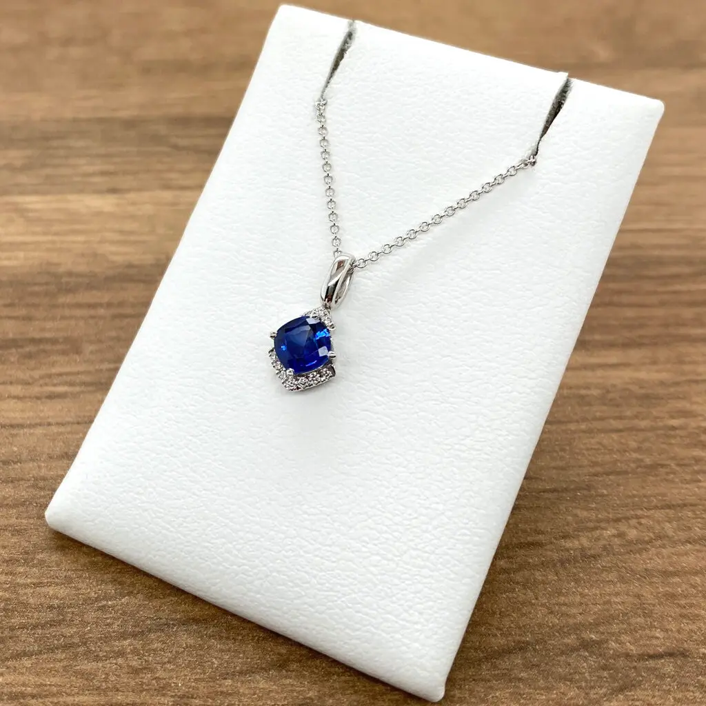 A blue sapphire and diamond necklace on a white background.